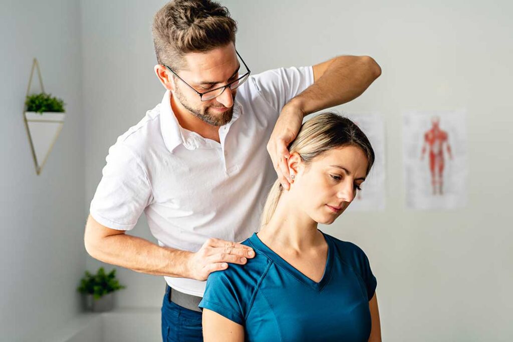 Patient discusses back pain with a chiropractor during a calm examination in a bright clinic room.