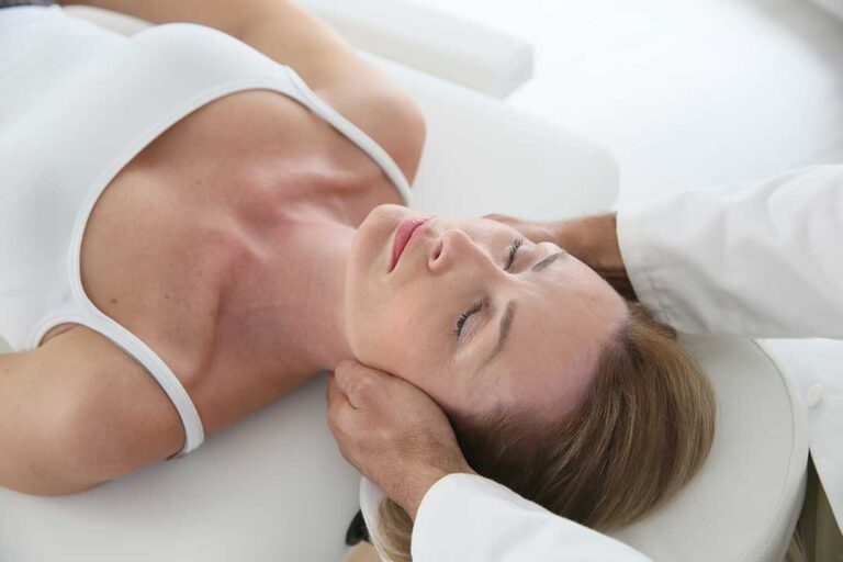 A person gently stretching their shoulder in a bright, clean home setting.