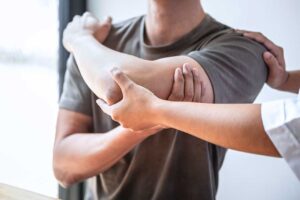 Athlete performing a supervised balance exercise while a clinician evaluates ankle movement.